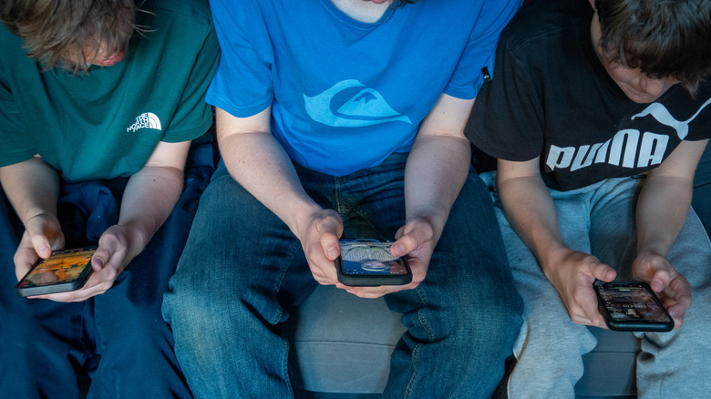 Three kids on their smartphones.