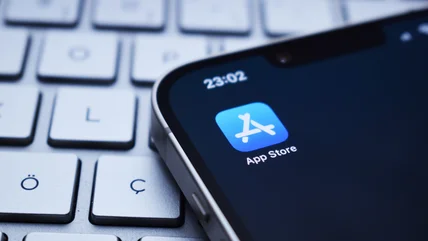 Close-up photo of an iPhone showing the App Store icon. The device is sitting on a wireless keyboard.