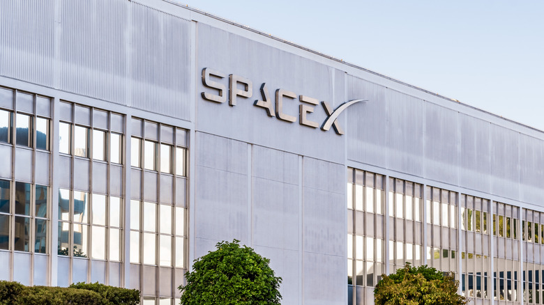 A building with grey siding and windows bears the SpaceX logo.