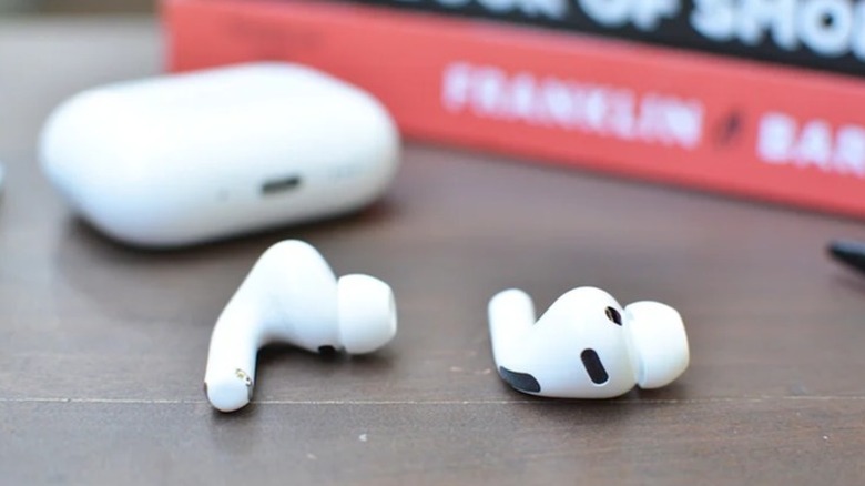 A pair of AirPod Pro 3 buds with their case, sitting on a desk.