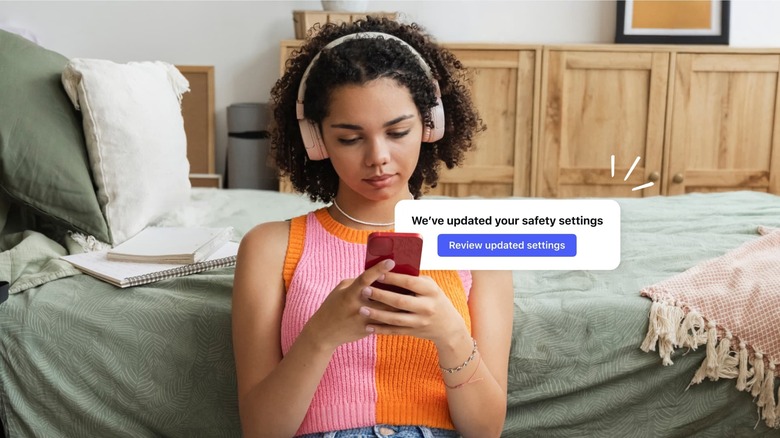 A young person looks at their phone while wearing headphones. A notification is overlaid. It reads 