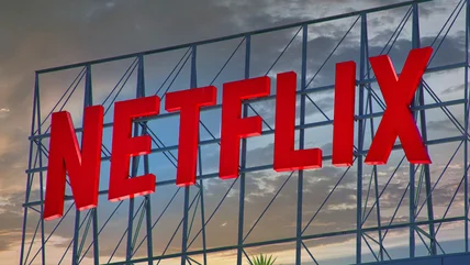 Photo of the Netflix logo on a sign with a cloudy sunset in the background
