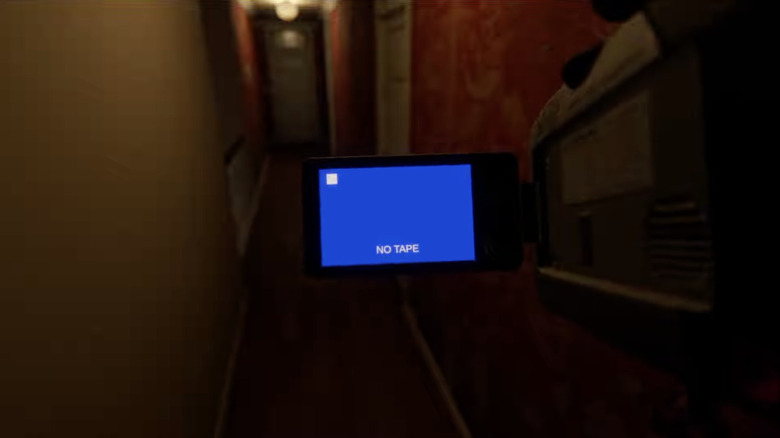 Screenshot of the trailer for Paranormal Activity: Threshold. First-person view shows a hand-held video camera with a blue screen reading 