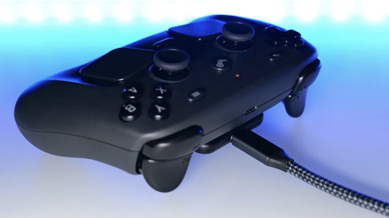 Photo of a black Steam Controller on a table lit by the reflected blue lights of a screen.
